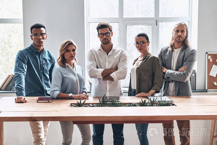 一群严肃的商务人士团队在木桌在创造性的现代办公室工作室摆姿势和