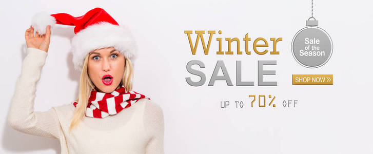 冬天销售消息与愉快的年轻妇女与圣诞老人帽子