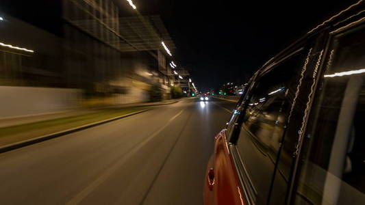 在城市的一条夜航大道上, 在一条夜航大道上行驶, 道路上的灯光在高速上反射在汽车上。现代城市的快速节奏