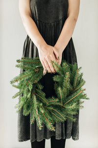 年轻女子拿着用冷杉树枝做的花环。圣诞节新年作文