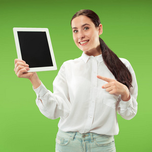 一个自信的休闲女孩的肖像显示空白屏幕的笔记本电脑孤立在绿色背景