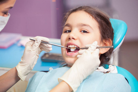 漂亮的小女孩开口宽在治疗她的牙齿的牙医的特写镜头