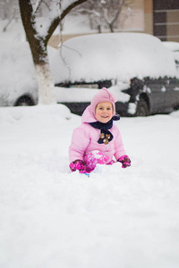 这孩子在冬天玩雪。一个穿着鲜艳夹克头戴针织帽子的小女孩, 在冬季公园里捕捉雪花过圣诞节。孩子们在被雪覆盖的花园里玩耍和跳跃