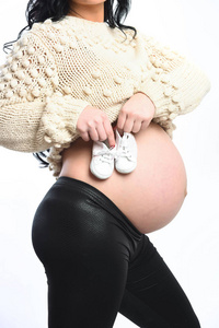 女手中孕妇肚子上抱着的婴儿鞋