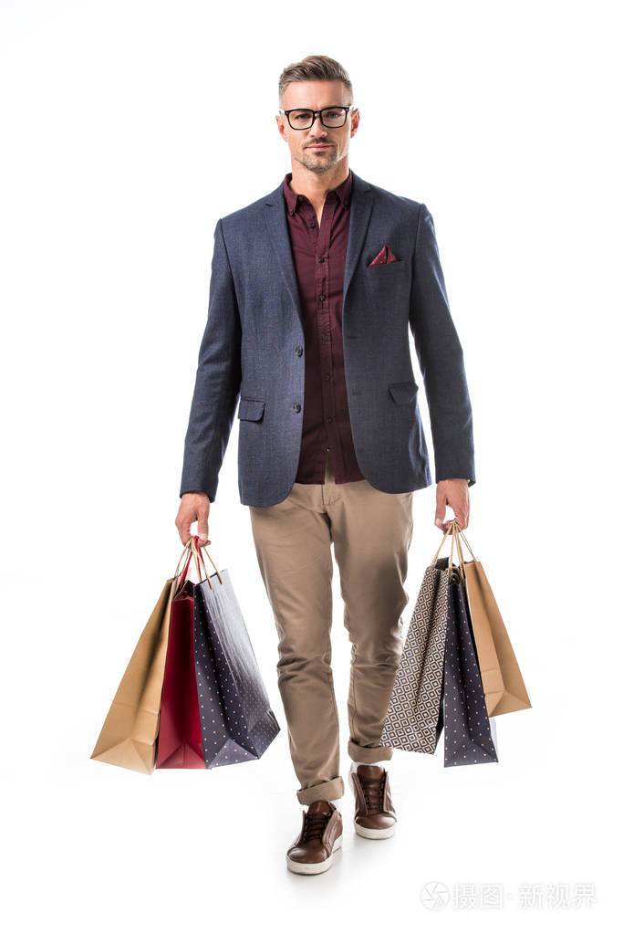 时尚的男人在眼镜和夹克拿着五颜六色的购物袋孤立在白色照片-正版商
