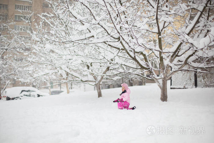 这孩子在冬天玩雪。一个穿着鲜艳夹克头戴针织帽子的小女孩, 在冬季公园里捕捉雪花过圣诞节。孩子们在被雪覆盖的花园里玩耍和跳跃