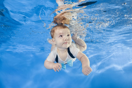 小男孩游泳在水下在水池里