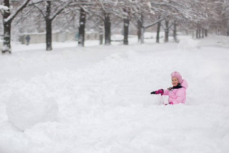 这孩子在冬天玩雪。一个穿着鲜艳夹克头戴针织帽子的小女孩, 在冬季公园里捕捉雪花过圣诞节。孩子们在被雪覆盖的花园里玩耍和跳跃