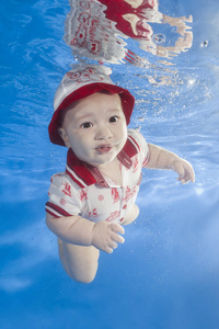 一个戴红帽的小男孩正在游泳池里游泳。