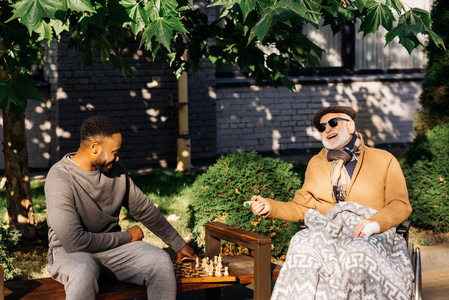 高级残疾人在轮椅和非洲裔美国人奎达多一起在街上下棋