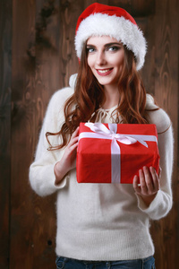 快乐兴奋的年轻女子在圣诞老人帽子与礼品盒灰色背景