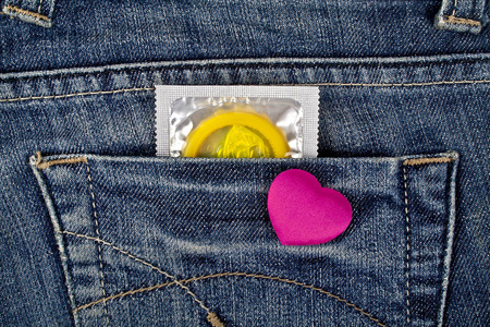 紫心和黄色蓝色牛仔裤口袋里的避孕套