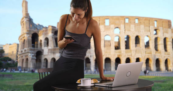 罗马体育馆附近的餐桌上的女游客, 在咖啡短信和笔记本电脑上