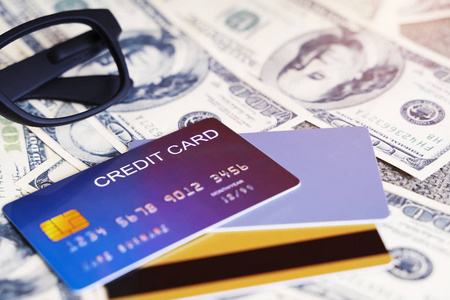 蓝色信用卡的特写镜头与模糊的美元在背景上。商业和金融概念