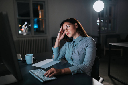 人打哈欠的肖像,深夜独自在黑暗的办公室里用笔记本电脑和文件加班