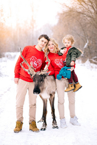 幸福的家庭和鹿的画像下冬季雪。新年, 圣诞节, 节日, 冬天, 家庭, 幸福的概念
