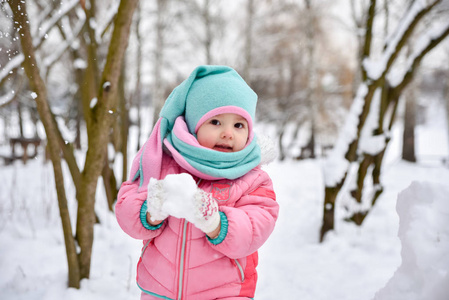 穿着粉色连身衣的小女孩走在雪天公园里