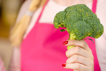 妇女在厨房拿着绿色新鲜的花椰菜。家庭主妇做饭。健康饮食素食节食和人的概念