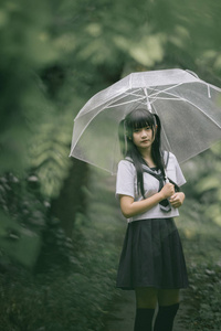 在雨中漫步在自然人行道上的亚洲学校女孩肖像