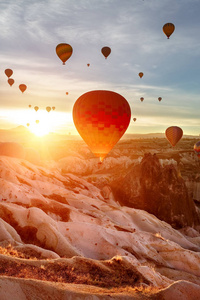 彩色气球上升到天空中。日出。太阳的光线照进照相机的镜头里。土耳其, 卡帕多西亚