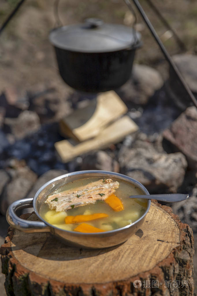 在火上做饭.火上的鱼汤.火上大锅里的食物.户外食物.在户外烹饪.