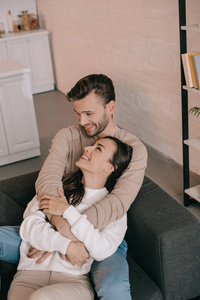 高视角的微笑的年轻夫妇拥抱在沙发上在家里