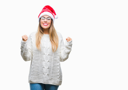 年轻美丽的妇女戴着圣诞节帽子在孤立的背景庆祝惊讶和惊讶的成功与双臂举起和睁开眼睛。获奖者概念