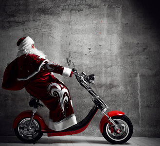 圣诞老人骑摩托车摩托车滑板车与袋子充满了礼物礼物与文字复制空间。新年和圣诞快乐