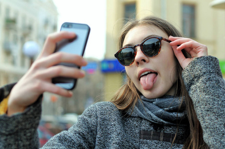 女孩做上她的手机拍照和显示的舌头
