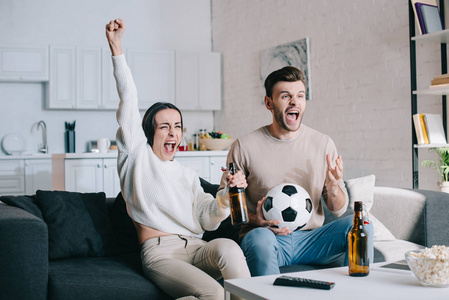 富有表现力的年轻夫妇在家里看足球比赛, 欢呼