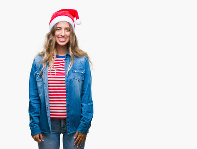 美丽的年轻金发女子戴着圣诞节帽子在孤立的背景与一个愉快和凉爽的笑容在脸上。幸运的人