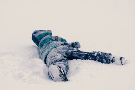 男孩躺在雪地里滚动从一边到一边