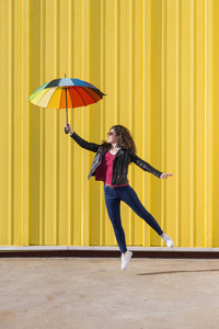 年轻女子跳和五颜六色的雨伞爱玩