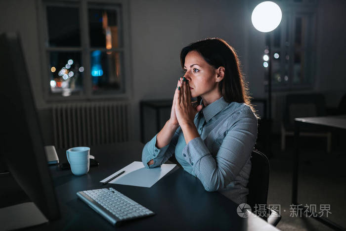 深夜工作.在加班时看电脑屏幕的严肃女实业家的侧面视图