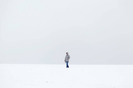 一个穿着灰色羽绒服的人在雪原地里