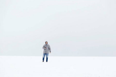 一个穿着灰色羽绒服的人在雪原地里