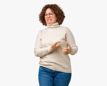 美丽的中年老年妇女穿着高领毛衣, 眼镜在孤立的背景厌恶的表情, 不满和害怕做厌恶的脸, 因为厌恶的反应。举起手来。令人讨厌的概念