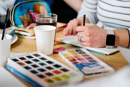 水彩绘画用画笔绘制在记事本上的妇女的手的特写的创建过程