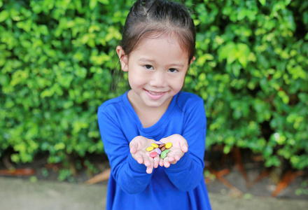特写亚洲小女孩拿着彩色涂层巧克力糖果在她的手中