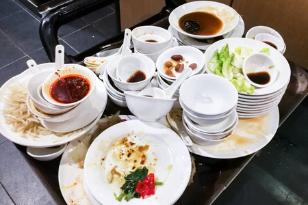 餐具脏饭后成堆的脏油盘子,碗和餐具照片