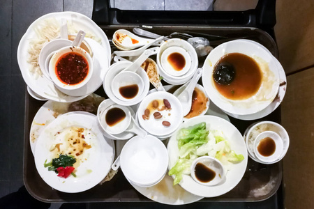 餐具脏饭后成堆的脏油盘子,碗和餐具照片