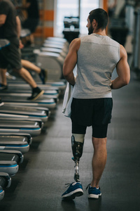 运动员的后视镜与人工腿走在健身房