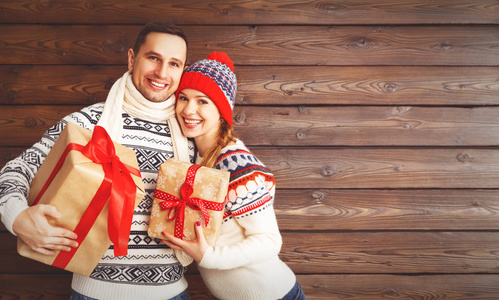 幸福的家庭夫妇与木制背景上的圣诞礼物