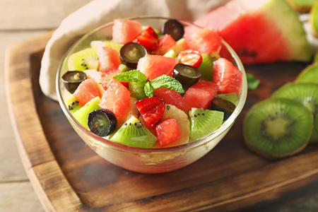 碗与美味的西瓜沙拉在木板上照片