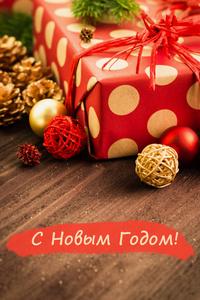 圣诞节和元旦节日节日装饰, 金球, 金色冷杉锥与礼物包裹在红色的纸与金色圆圈在棕色木头背景与文本新年快乐 在俄罗斯新年快乐 