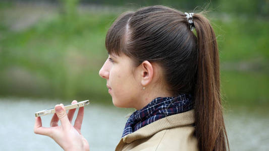 谈到智能手机室外春天的女孩。特写