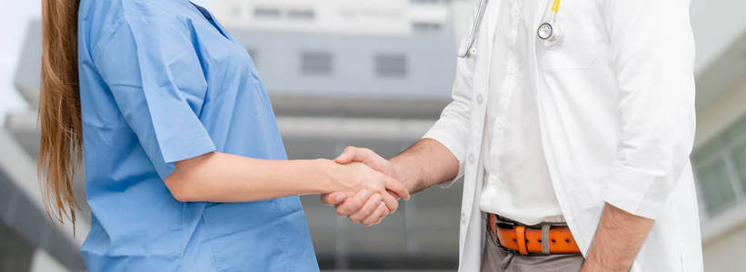 医生在医院与另一位医生握手。医护人员团队合作与医疗服务理念