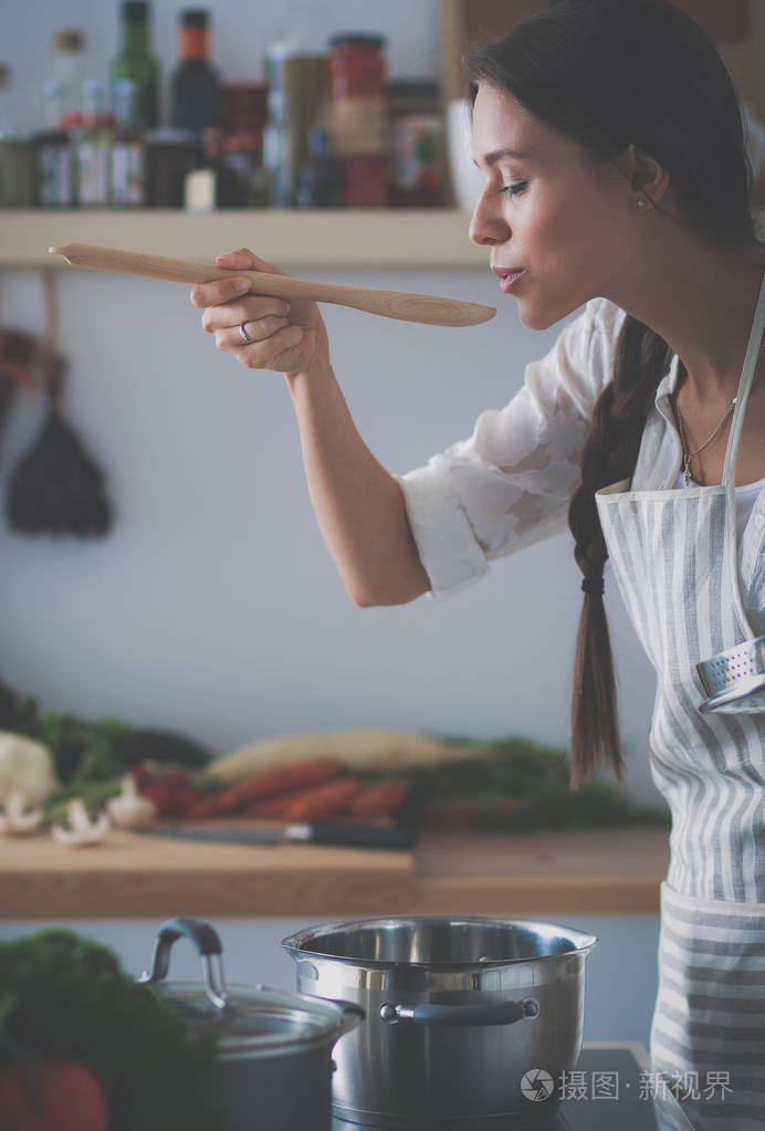 烹饪的女人,在厨房里用木勺