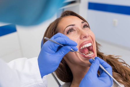 年轻自信的男性牙医在诊所给一名女性患者治疗。牙科诊所的概念