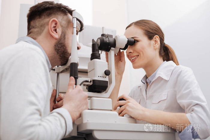 快乐的专业眼科医生扫描她的病人的眼睛